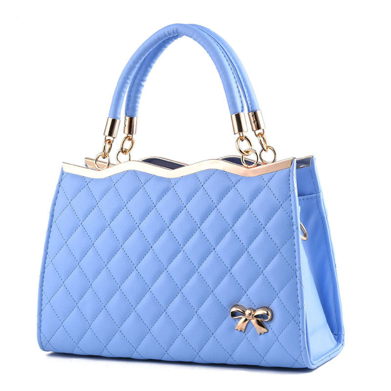 Light blue handbag with a gold bow detail on a white background