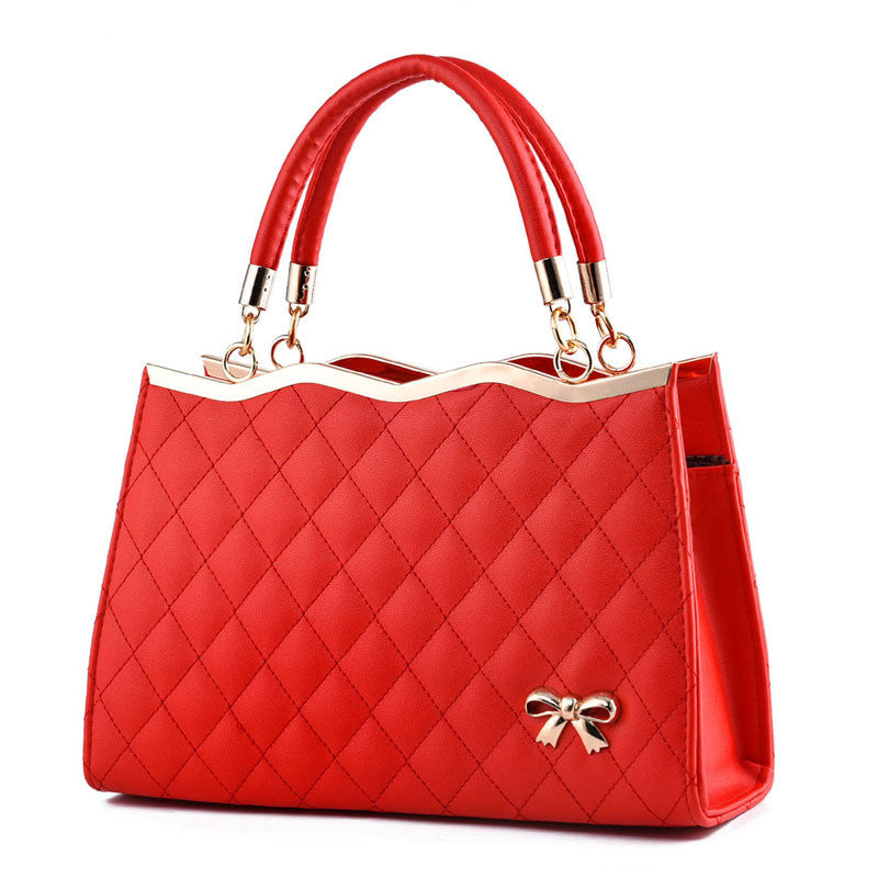 Red quilted handbag with a bow detail on a white background