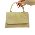 Gold handbag held by a hand with red nail polish on a white background