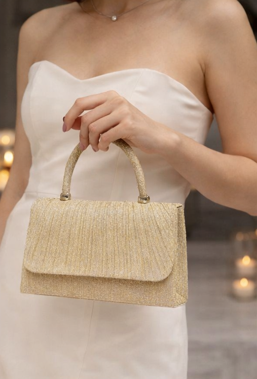 Woman holding aa sparkly gold handbag while out