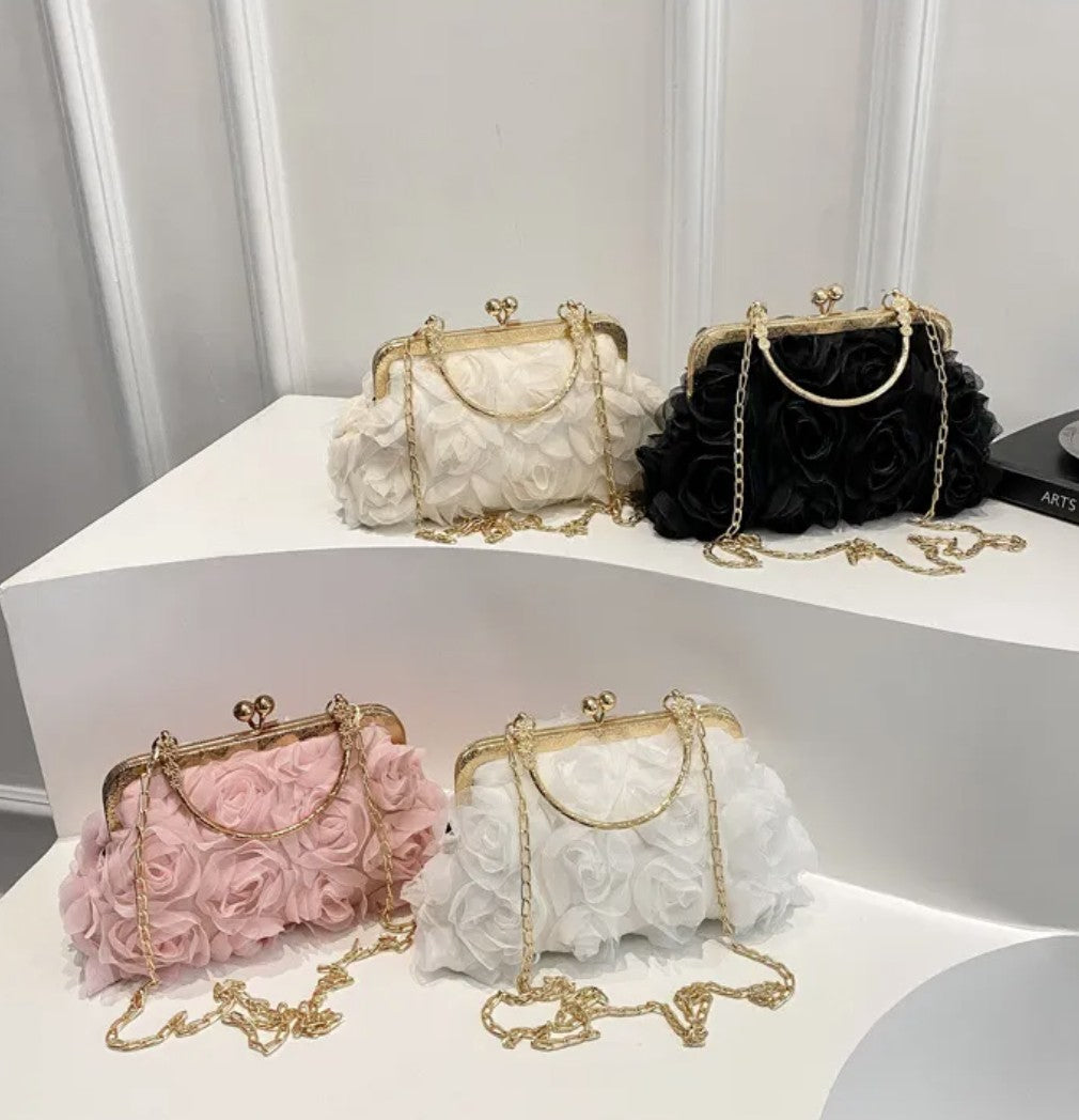 Four floral handbags in white, black, pink, and gold on a white surface with a gray wall background.