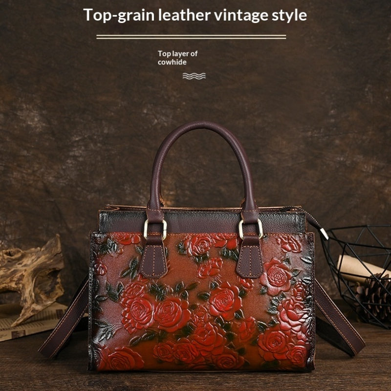 Brown leather handbag with floral embossing on a dark background