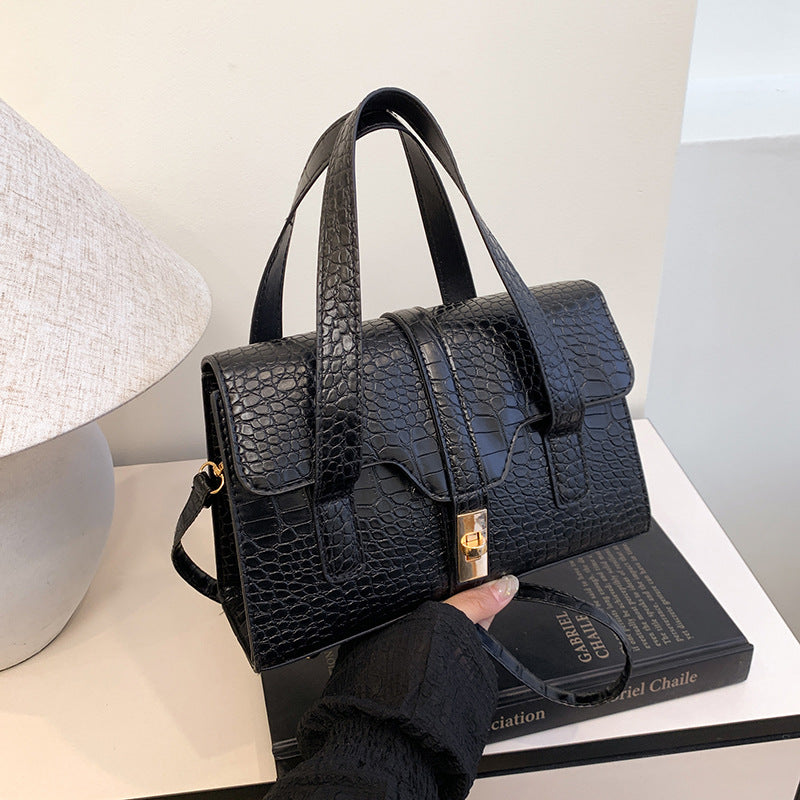 Black crocodile-patterned handbag being admired