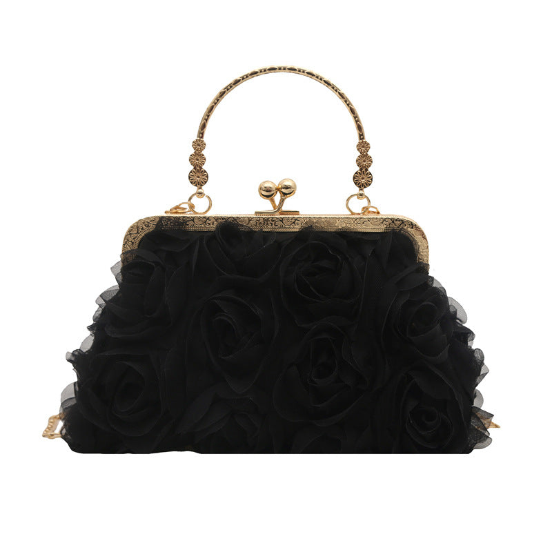 Black rose-patterned handbag with gold accents on a white background