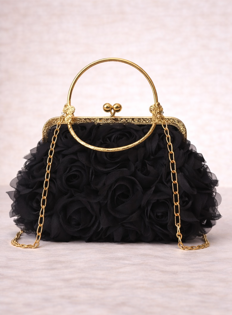 Black handbag with floral design and gold chain strap on a light background