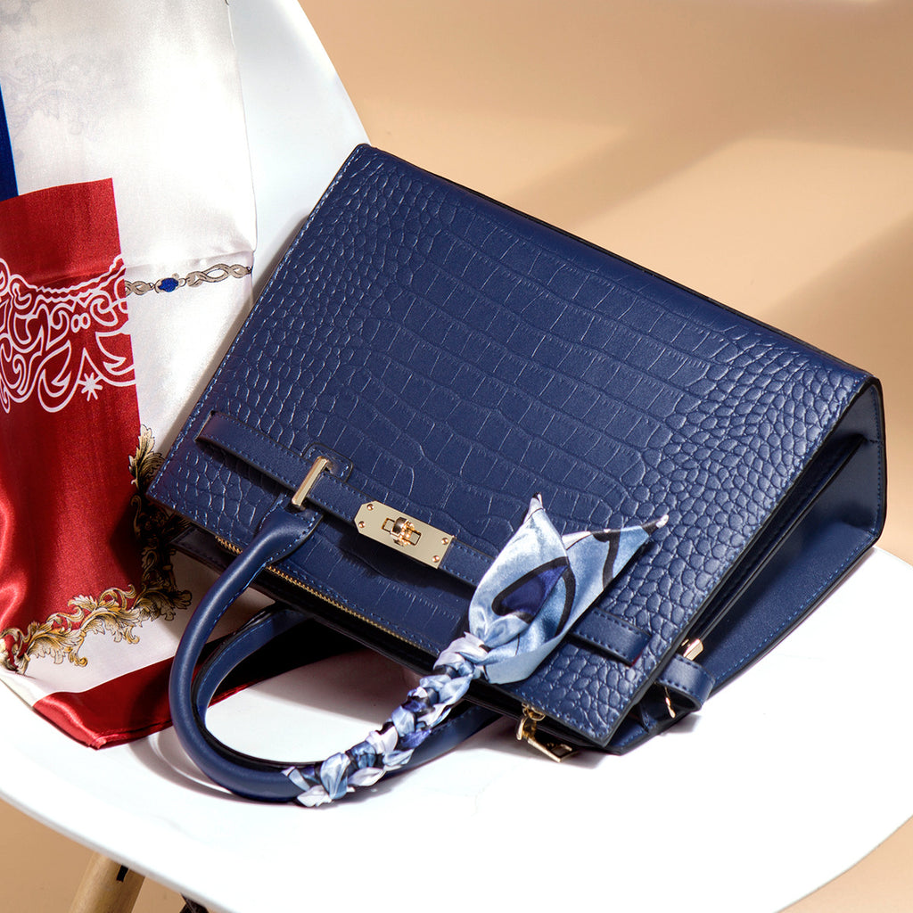 Blue handbag with a decorative strap on a beige surface
