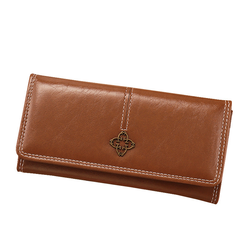 Brown leather wallet with a decorative charm on a white background