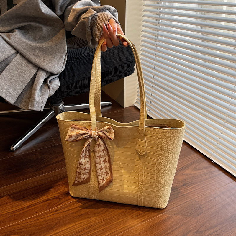 Cream handbag with a bow on a wooden floor