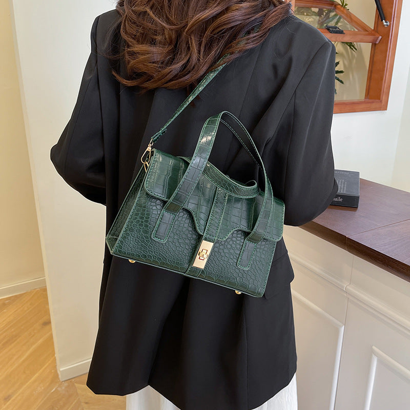 Woman wearing a black outfit with a green handbag in an indoor setting