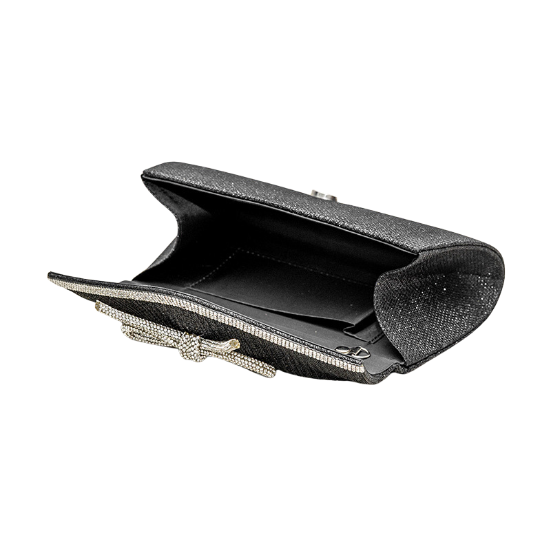 Black clutch bag with decorative bow on a white background opened