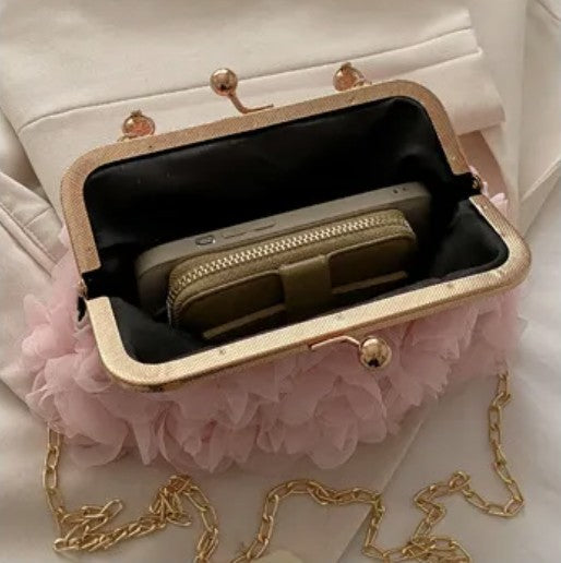 what fits inside the small handbag with pink floral details and gold chain strap on a light background