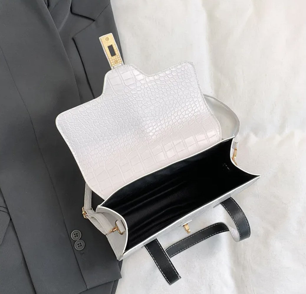 White handbag with black interior and handles, next to a grey jacket