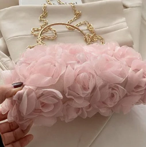 Pink floral clutch held by a hand with a white background