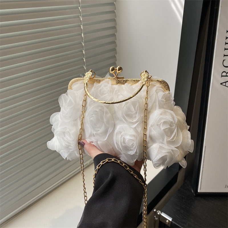 Handbag with white floral design held by a hand, with a blurred background