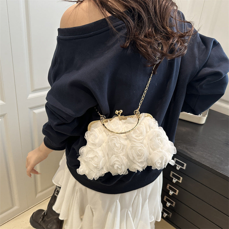 Person wearing a navy blue off-shoulder top and white floral handbag.